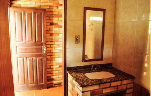 a bathroom with a sink and a mirror and a door at Moradas Girassol in Guarda do Embaú
