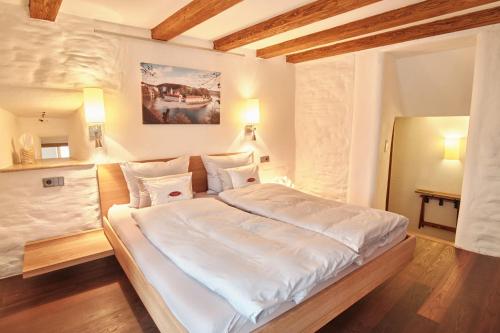 a bedroom with a large bed with white sheets at Turmhotel zum Erasmus in Kelheim