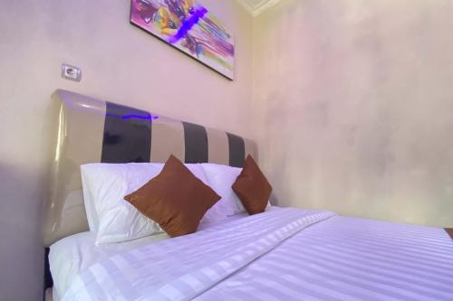 a bedroom with a bed with white sheets and pillows at Homestay Banteng Adventure Dieng Mitra RedDoorz in Dieng