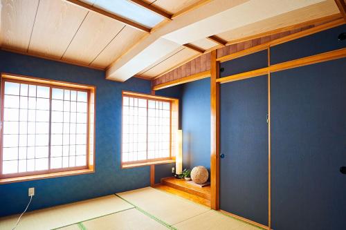 a room with blue walls and windows and a door at Terrace House Tsubokawa in Naha