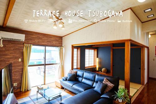 a living room with a blue couch and a large window at Terrace House Tsubokawa in Naha