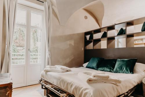 a bedroom with a bed with green pillows and a window at Le Dimore di Piazza in Mondovì