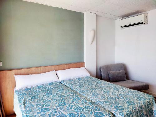 a small bedroom with a bed and a chair at Flats Friends Atlantida in Benidorm