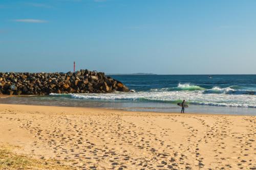 a man walking on the beach with a surfboard at Mantra The Observatory in Port Macquarie