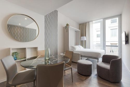 a living room with a table and chairs and a mirror at Brera Apartments in San Babila in Milan
