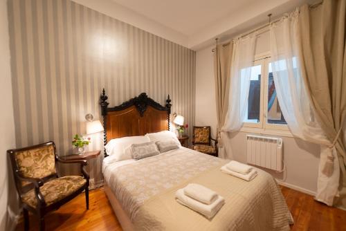 a bedroom with a bed and a chair and a window at Heart of Pamplona Palace in Pamplona