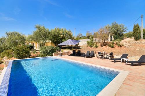 a blue swimming pool with chairs and a gazebo at Villa Poço Geraldo, Piscina BBQ Prestige For Home in Loulé