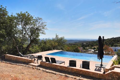 a swimming pool with chairs and an umbrella at Villa Poço Geraldo, Piscina BBQ Prestige For Home in Loulé