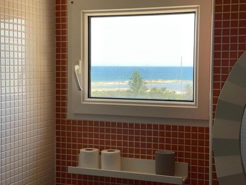 een badkamer met een raam en een plank met toiletpapier bij El Remanso III in La Manga del Mar Menor