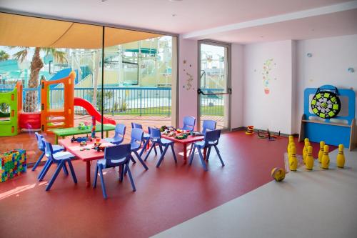 uma sala de jogos com mesa e cadeiras e um parque infantil em Atlantica Aqua Blue em Protaras