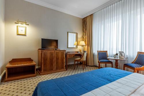 a hotel room with a bed and a desk and a television at Natsionalny Hotel in Kyiv