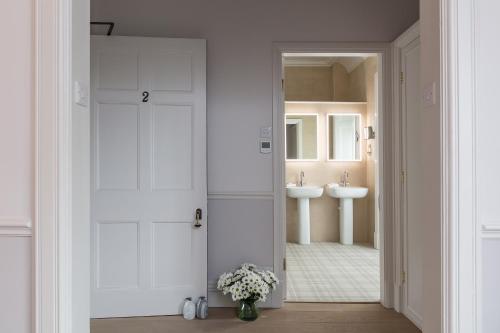 a bathroom with white cabinets and a sink at Farlam Hall Hotel & Restaurant in Brampton