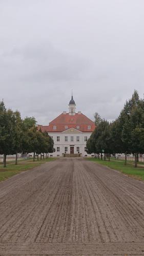 an empty dirt road in front of a large white building at Fewo in Neustadt/Dosse, der Stadt der Pferde in Leddin