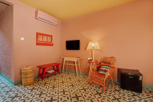 a living room with a chair and a tv at Por Aqui Stay & Dine in Yogyakarta