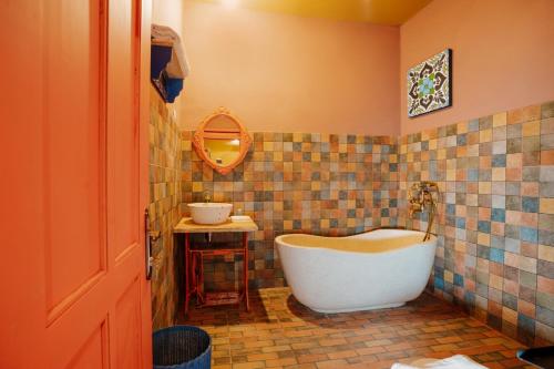 a bathroom with a tub and a tiled wall at Por Aqui Stay & Dine in Timuran