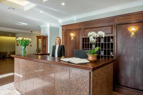 a woman is standing in front of a large desk at Ratonda Centrum Hotels in Vilnius
