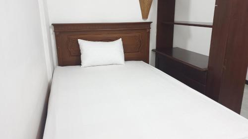 a white bed with a wooden headboard and a white pillow at Castle Residence Syariah RedPartner in Siwalapkerto