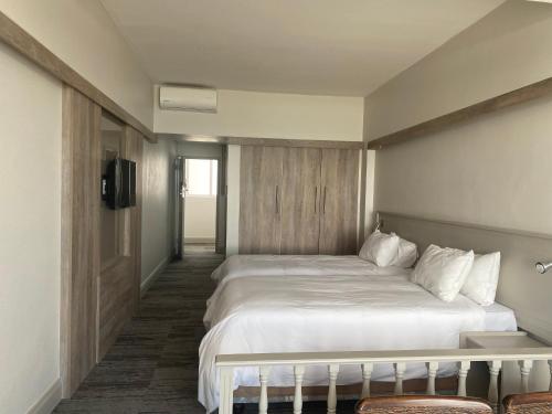a bedroom with a large white bed and a television at Kennaway Hotel in East London