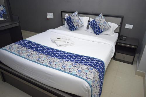 a large bed with blue and white sheets and pillows at Viswa Residency by Azalea in Madurai
