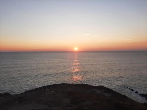a sunset over the ocean with a rock in the foreground at Bude Coastal Lodge in Bude
