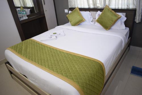 a large bed with green pillows on top of it at Viswa Residency by Azalea in Madurai