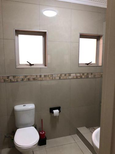a bathroom with a toilet and a sink and two windows at Afsaal flats in Amanzimtoti