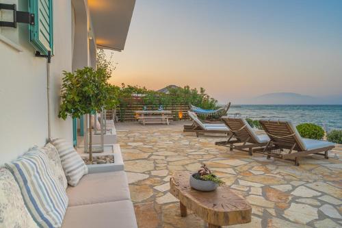 patio z krzesłami i stołem oraz oceanem w obiekcie Anemos Beach House w Alikanás