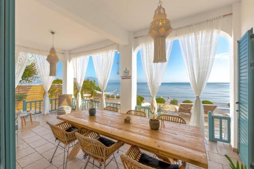 Anemos Beach House في اليكاناس: غرفة طعام مع طاولة وكراسي والمحيط