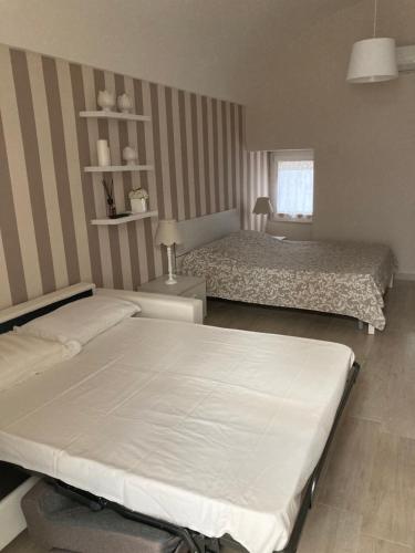 a bedroom with two beds and a striped wall at Casa Via della Stazione in Noci