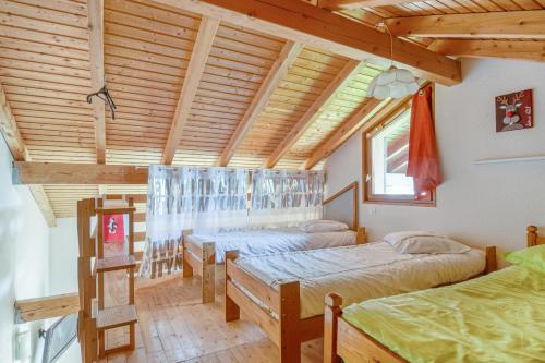 une chambre avec deux lits et un plafond en bois dans l'établissement Le Lutin, à La Bresse