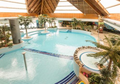 une grande piscine avec des palmiers dans un immeuble dans l'établissement Le Saphir, à Branville