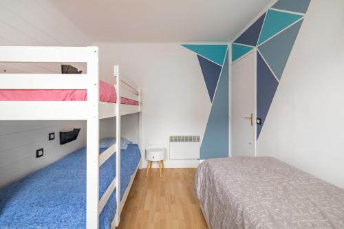 a bedroom with bunk beds and a blue and white wall at Le Saphir in Branville