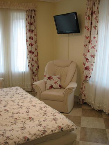 a bedroom with a chair and a tv on the wall at Aranyosház-Vendégház in Budapest