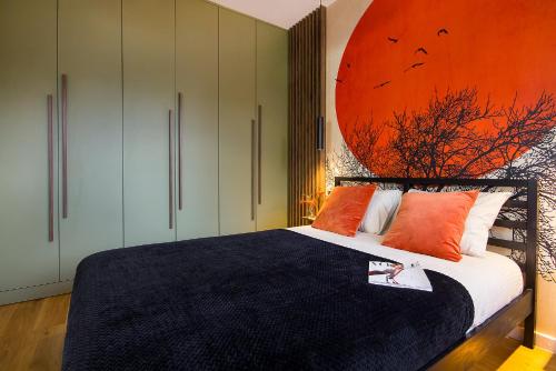 a bedroom with a bed with an orange painting on the wall at W&K Apartments - Balance Suite in Koszalin