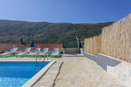 a swimming pool with lounge chairs and a fence at Holiday Home Dijamant in Kučiće