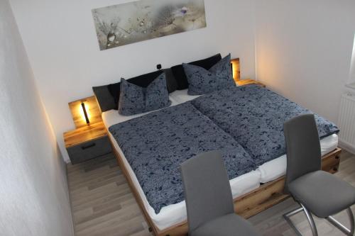 a bedroom with a blue bed with two chairs at Ferienwohnung Löffler Nassau-Erzgebirge in Frauenstein