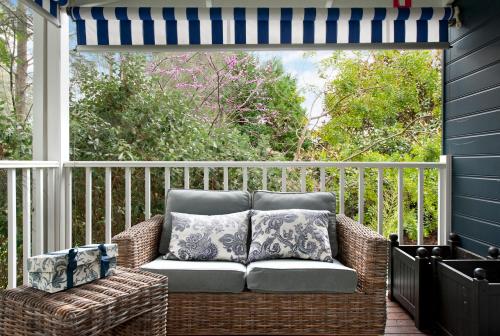a wicker chair on a porch with a window at Bells at Killcare Boutique Hotel, Restaurant & Spa in Killcare