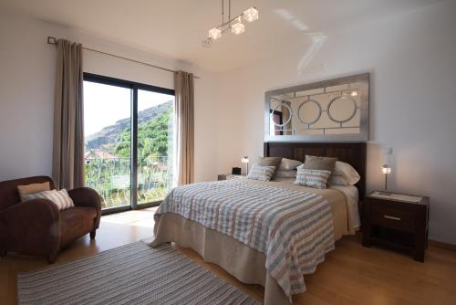 een slaapkamer met een bed en een groot raam bij Luxury Ocean Front Villla in Calheta