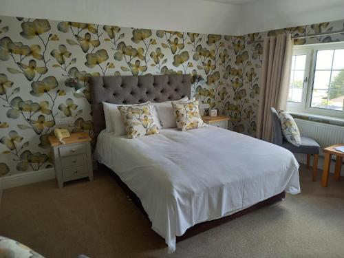 een slaapkamer met een groot wit bed met bloemen aan de muur bij Trelawne Hotel in Falmouth