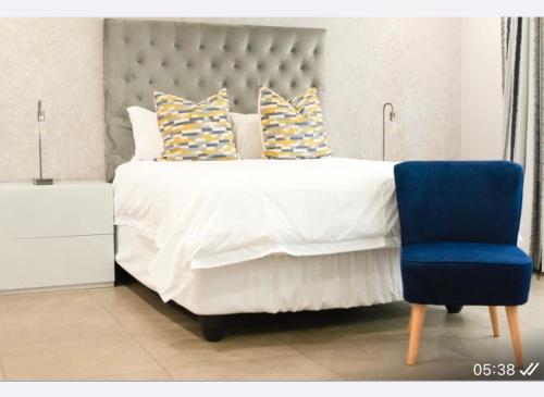 a bedroom with a large bed with a blue chair at Precious Paradise Villa in Amanzimtoti
