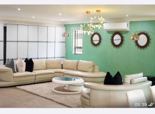 a living room with a couch and two mirrors at Precious Paradise Villa in Amanzimtoti