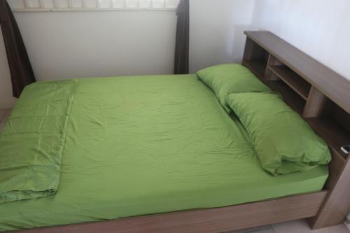 Una cama con una manta verde encima. en Dubbel woonhuis Selderiestraat Paramaribo, en Paramaribo