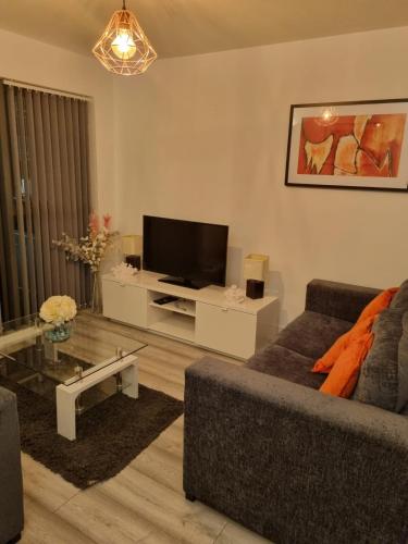 a living room with a couch and a flat screen tv at The Symphony Apartment in Liverpool