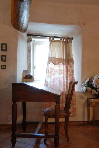 a piano with a chair in front of a window at Maison d'hôtes Ferme de la Commanderie in Richerenches