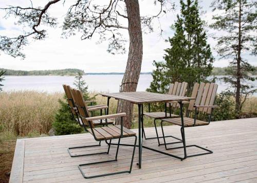 una mesa y sillas en una terraza de madera con un lago en Glamping in the Trosa Archipelago, en Trosa