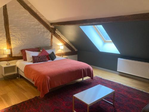 een slaapkamer met een groot bed en een rode deken bij B&B Les Oiseaux de Passage in Harre