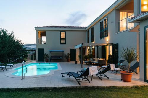 a patio with chairs and a pool in front of a house at Villa Marta Luxury House with Heated Pool in Plano