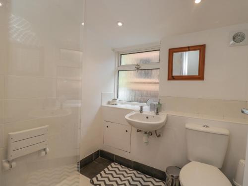 a white bathroom with a toilet and a sink at The Anchorage in Shepton Mallet