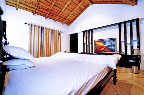 1 dormitorio con 1 cama blanca grande y ventana grande en Vibhasa-Dhaulagiri Room in Adventure Bliss Villa Where Scenic Views Meet BBQ and Bonfire Delights en Rāmgarh