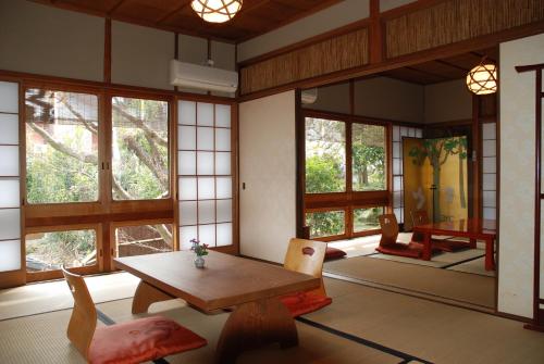 um quarto com uma mesa, cadeiras e janelas em Yadoya Manjiro em Quioto